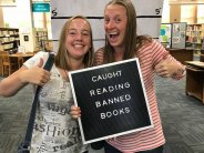 Two patrons holding a caught reading banned books sign.