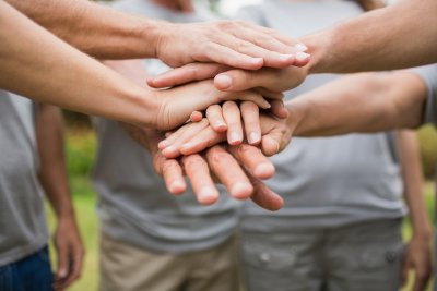 Photo of group of volunteers grouped into a circle stacking their hands one on top of the other