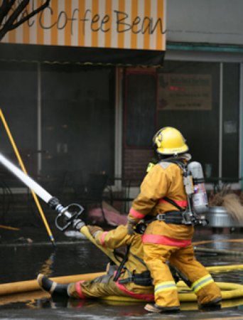 Firefighters blast a burning building with water from a high pressure fire hose